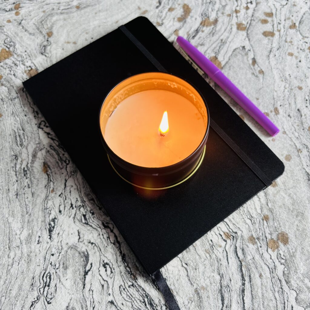 Lit candle on a journal with a pen