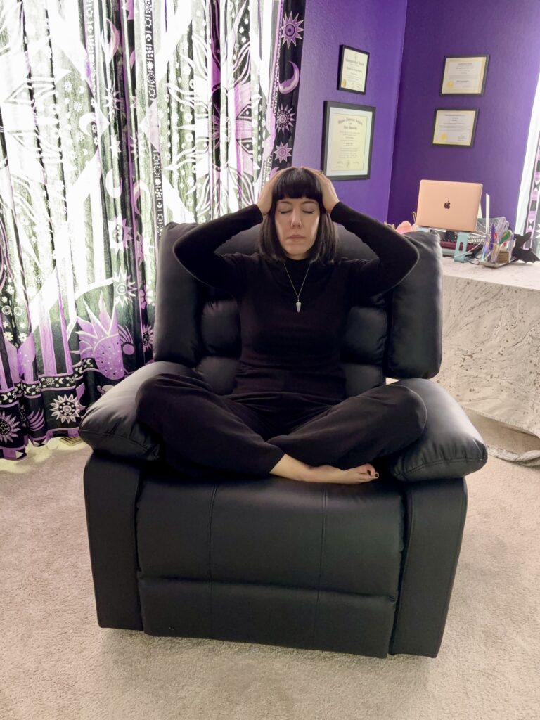 Woman sitting in a recliner performing self-Reiki