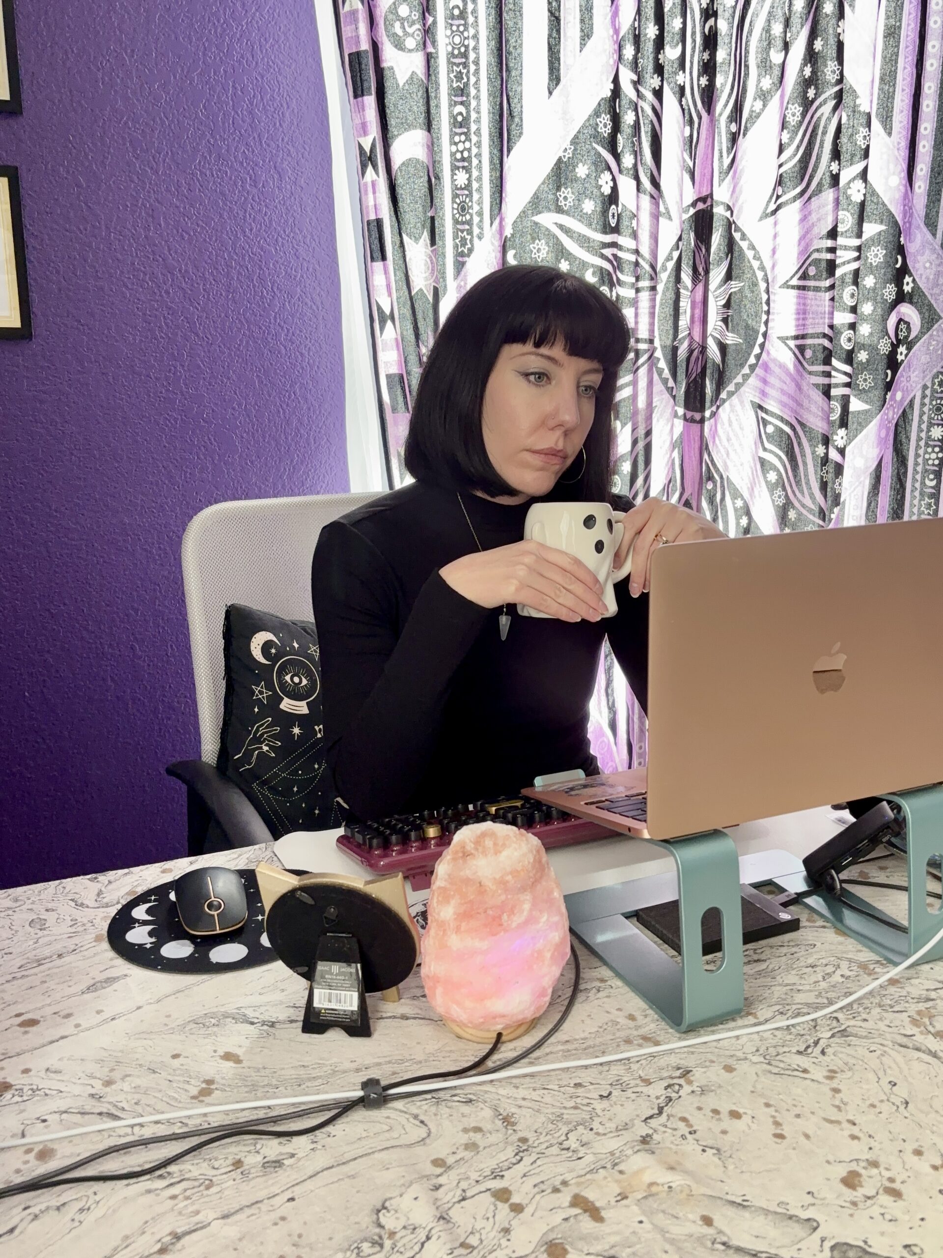 Woman holding a ghost shaped mug working on her laptop