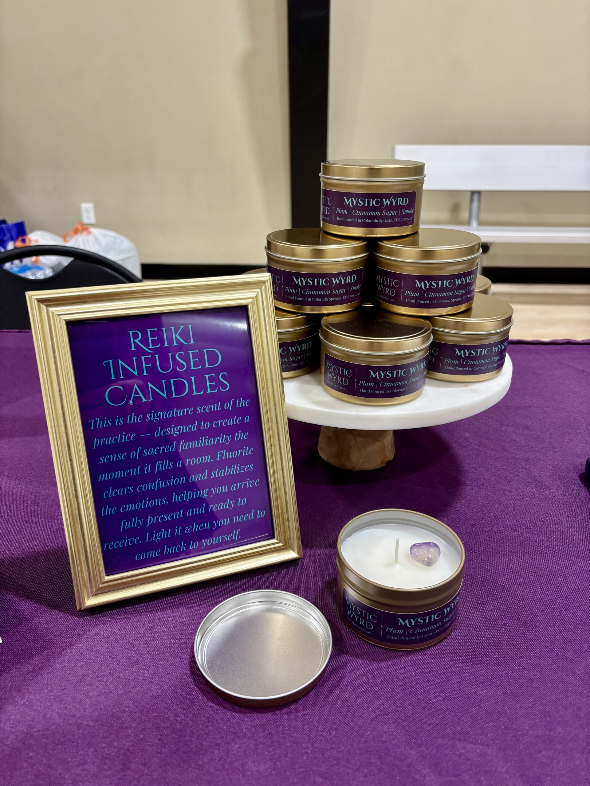 Candles in gold tins in a pyramid display next to a sign about Reiki-infused candles