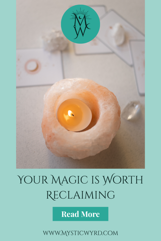 Candle with crystals and oracle cards and the words, "Your magic is worth reclaiming."